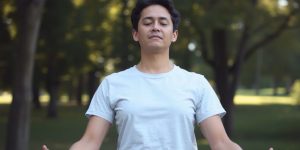 Person practicing relaxation breathing in a serene outdoor setting.